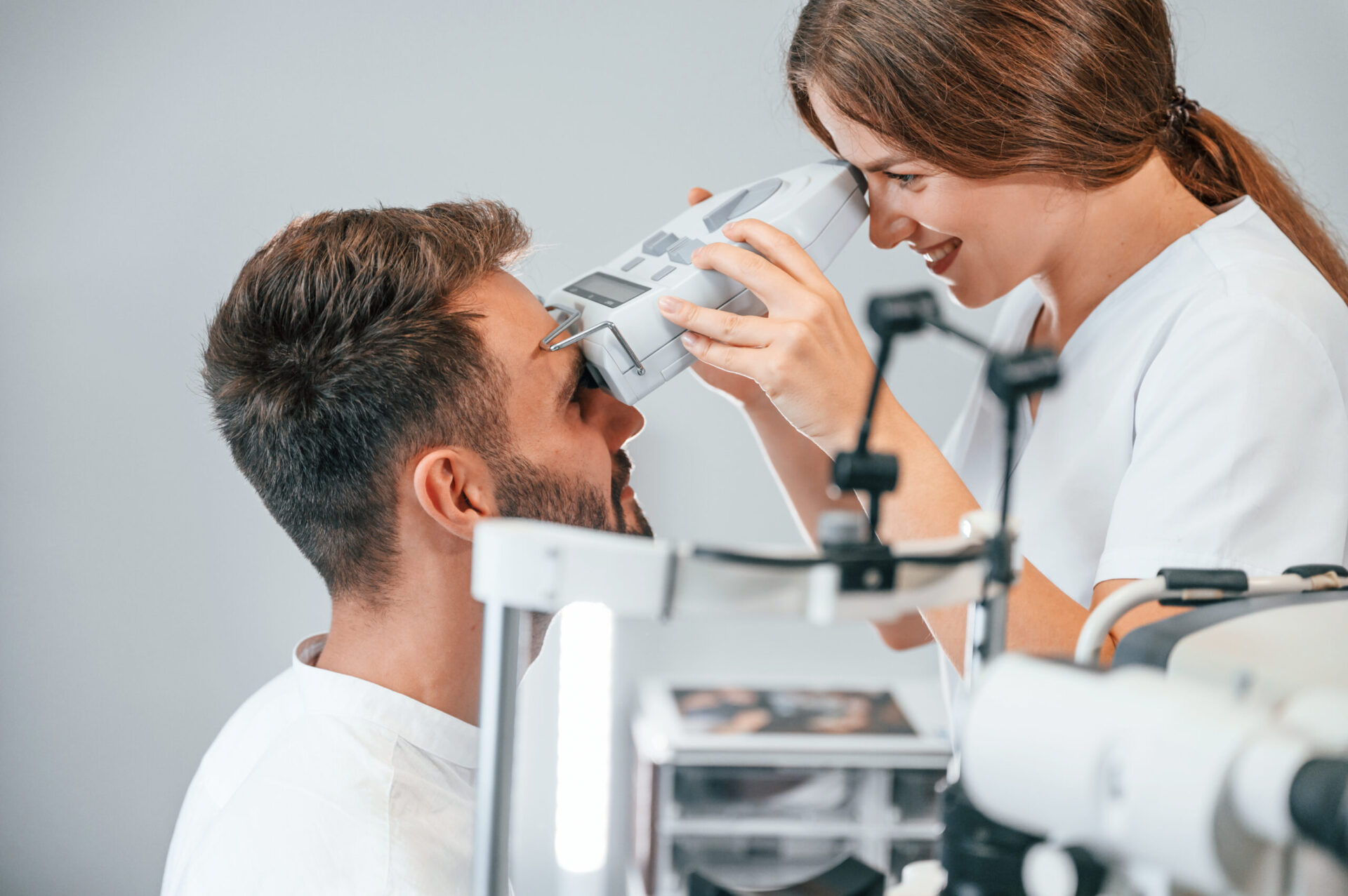 Modern technologies. Man's vision checked by female doctor in the clinic by using special optometrist device.